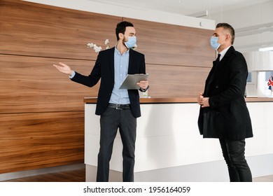 Salesman And Customer In A Car Dealership Wearing Masks During Pandemic