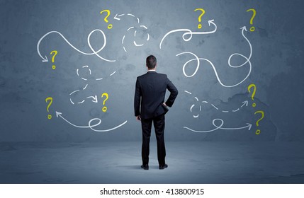 A salesman in doubt can not find the solution to the problem concept with curvy lined arrows and question marks drawn on urban wall - Shutterstock ID 413800915