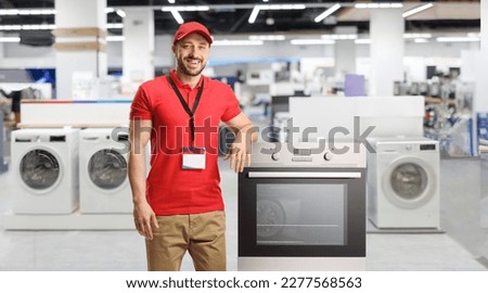 Salesman with electrical appliances smiling and leaning on an oven inside a store