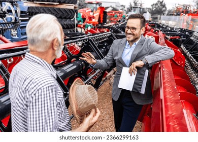 Salesman and farmer discussing about farming equipment and purchase of agricultural machinery. - Shutterstock ID 2366299163