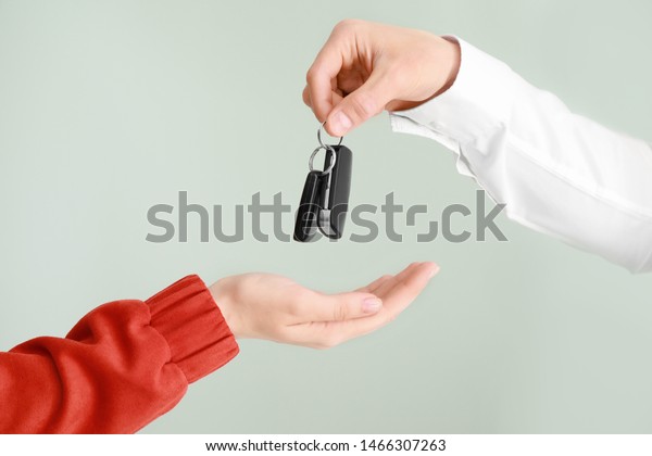 Salesman\
giving car keys to woman on light\
background