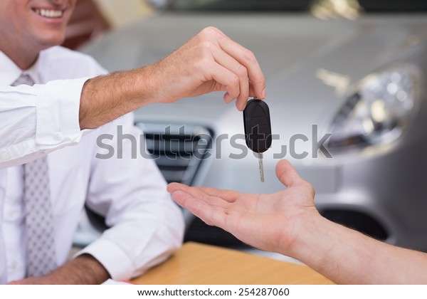 Salesman\
giving a customer car keys at new car\
showroom