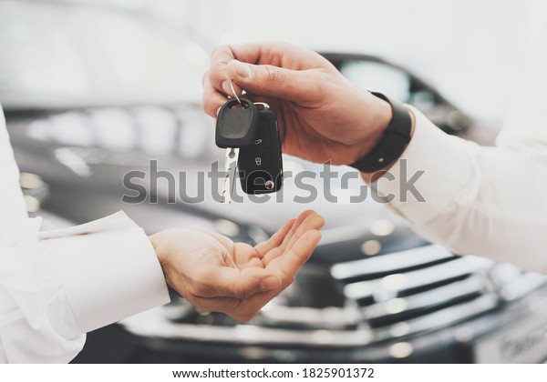 Salesman is giving keys for new car to man\
and his wife. The seller gives the keys to the Arab hands of a new\
car in a car\
dealership.