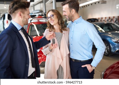 Salesman Handing Couple Brand New Car Keys
