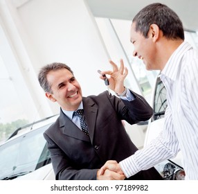 Salesman Handling Keys To A Man After Buying A Car