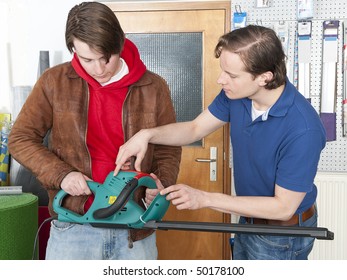 Salesman At A Hardware Store Demonstrating And Selling Hedge Shears To A Customer