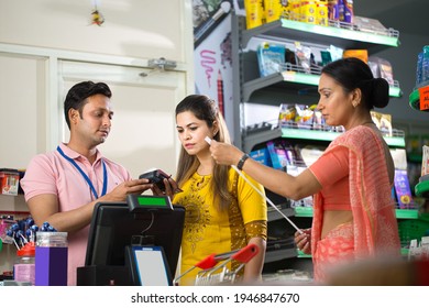 Salesman Helping Woman With Product Information At Checkout Counter Of Grocery Store