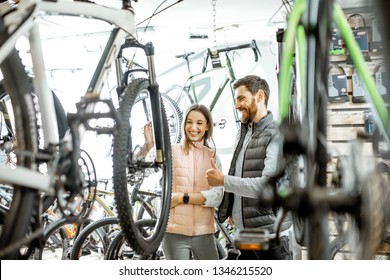 Salesman helping young woman to choose a new bicycle to buy standing in the bicycle shop - Powered by Shutterstock