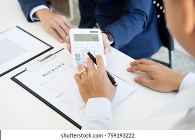 salesman holding a key and calculating a price at the dealership office to buyer for car insurance price