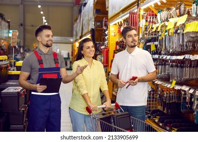 Salesman at a modern hardware store helping customers. Husband and wife shopping for tools at a DIY store. Young married couple buying goods for different home repairs at a hardware shopping centre