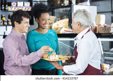 Salesman Offering Cheese Samples To Customers In Shop - Shutterstock ID 414153787
