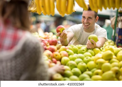 salesman offers an apple at street market