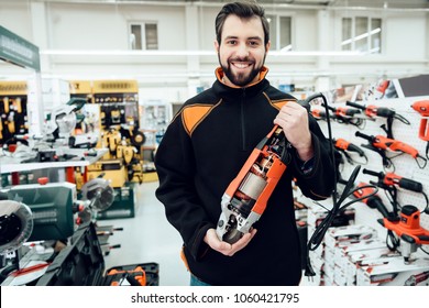 Salesman Is Posing With New Disc Grinder In Aisle Of Power Tools Store.