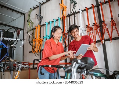 Salesman And Saleswoman Looking New Model Bike On Tablet Screen