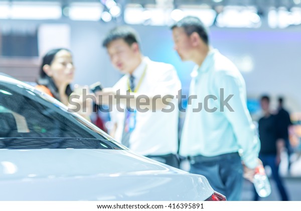 Salesman sell\
cars to customers at the auto\
show