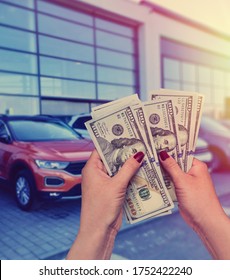 Salesman Selling Auto In Car Shop Or Businessman Buying New Car Holding Dollar In Hand.
