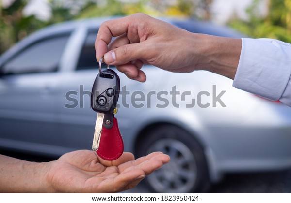 The salesman is sending the car keys to the\
hand of a female customer. After signing the contract between\
purchase - sale\
successfully