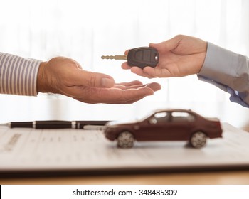 Salesman sends the car keys to the client. Concept of car insurance, rental, sales. - Shutterstock ID 348485309
