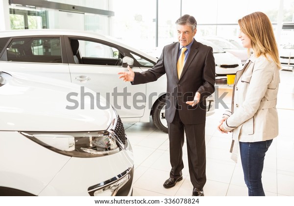 Salesman\
showing a car to a client at new car\
showroom