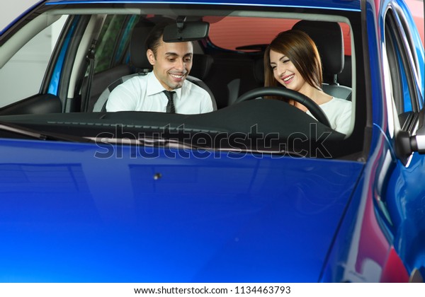 Salesman showing car\
inside for client. Woman is interisting in buying car. Sales man is\
going to make a deal