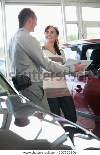 Salesman\
showing documents ta a woman in a car\
shop