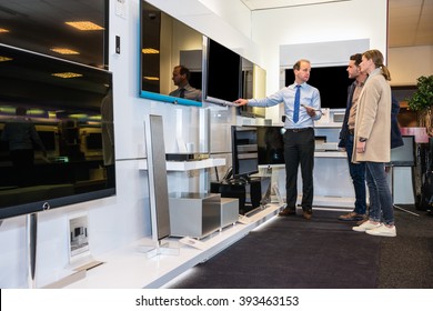 Salesman Showing Flat Screen TV To Young Couple In Electronics Store