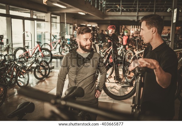 Salesman showing a new bicycle to interested\
customer in bike shop.