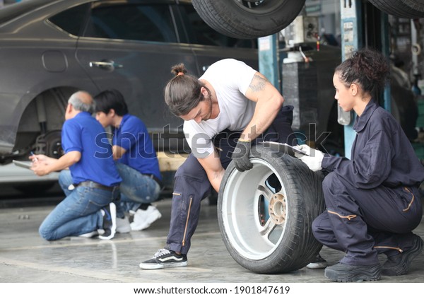 Salesman with\
showing wheel tires at car repair service or auto store, business,\
maintenance and people\
concept