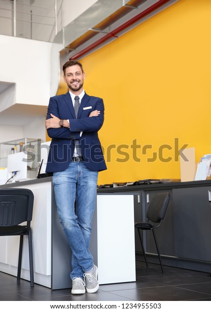 Salesman standing in modern auto dealership. Buying\
new car