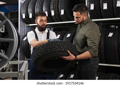 Salesman Of Tires Talking About Characteristic Of Product To Customer Came To Look At Assortment Represented In Auto Service Shop