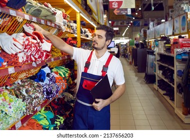 Salesman in uniform work in building hypermarket check products on shelves. Male consultant or assistant work restock goods in household or construction store. Shop assistance and consult.