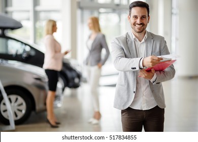 Salesperson At Car Dealership Selling Vehichles