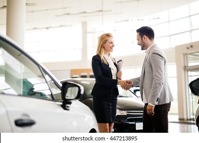 Salesperson Showing Vehicle To Potential Customer In Dealership