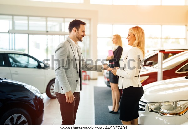 Salesperson showing vehicle to potential\
customer in\
dealership