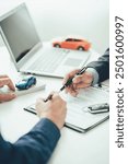 Salesperson at a table in a showroom Customer and new car, male car salesman stands beside and gives her advice Inside the shop where people sell cars Close-up pictures