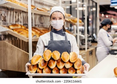 A saleswoman in bakery department offering tasty pastry at supermarket. - Shutterstock ID 2206116661