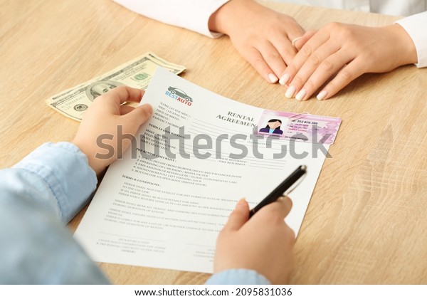 Saleswoman holding rental agreement on wooden\
table, closeup
