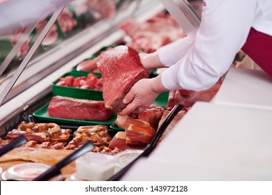 saleswoman offering fresh meat at display in supermarket