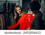 
Saleswoman Presenting a Blazer to her Fashion Store Customer. Happy buyer checking out formal wear in a mall boutique 
