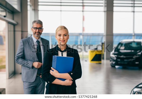 saleswoman and\
sales man in car dealership\
showroom