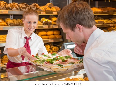 Saleswoman or shopkeeper in bakery presenting tablet with sandwiches to customer - Powered by Shutterstock