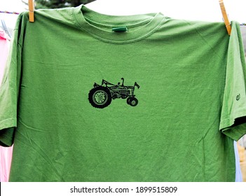 Salida, CO, USA. A Green Tee Shirt With A Vintage Farm Tractor Design Hangs On A Clothes Line For Sale At An Outdoor Craft Fair Vendor Booth. 09-09