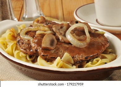 Salisbury Steak With Sauteed Mushrooms And Onions On Noodles In A Small Casserole Dish