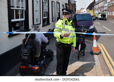 Salisbury, UK - July 6, 2018: A Police Officer Lifts Cordon Tape For A Man Driving A Mobility Vehicle As Investigations Continue Into The Nerve Agent Poisoning Of Charlie Rowley And Dawn Sturgess.