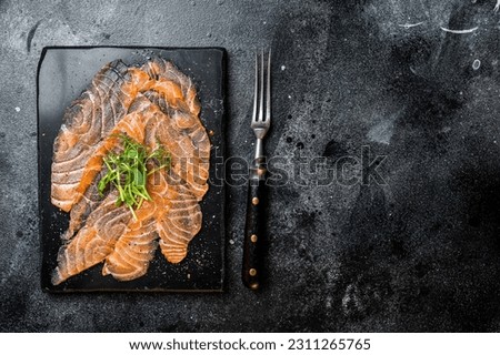 Salmon carpaccio with microgreens on marble board. Black background. Top view. Copy space.