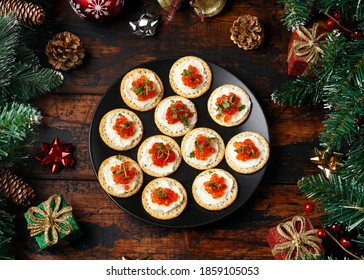 Salmon Caviar And Soft Cheese Savory Crackers With Decoration, Gifts, Green Tree Branch On Wooden Rustic Table.