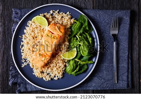 Salmon in Coconut Lime Sauce with brown rice and fresh spinach, salmon fish curry with rice and greens on a plat