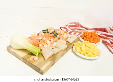 Salmon, Cod, Fennel On A Wooden Cutting Board. Potatoes And Carrots In White Plates. Spoon And Striped Tablecloth. Swedish Flags. Ingredients For Traditional Scandinavian Fish Soup. Swedish Food.