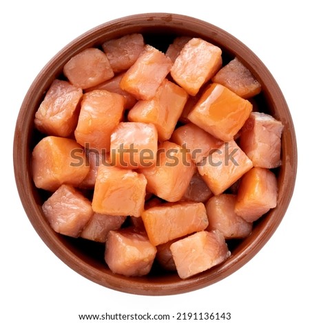 Salmon cut into small cubes in a bowl isolated on a white background, top view