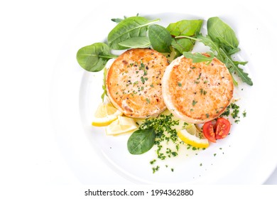 Salmon cutlets and spinach salad on a white plate